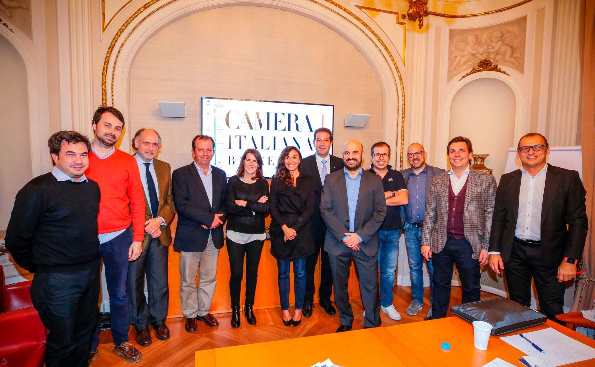 Group of people standing in a meeting room with a Camera Italiana sign behind them