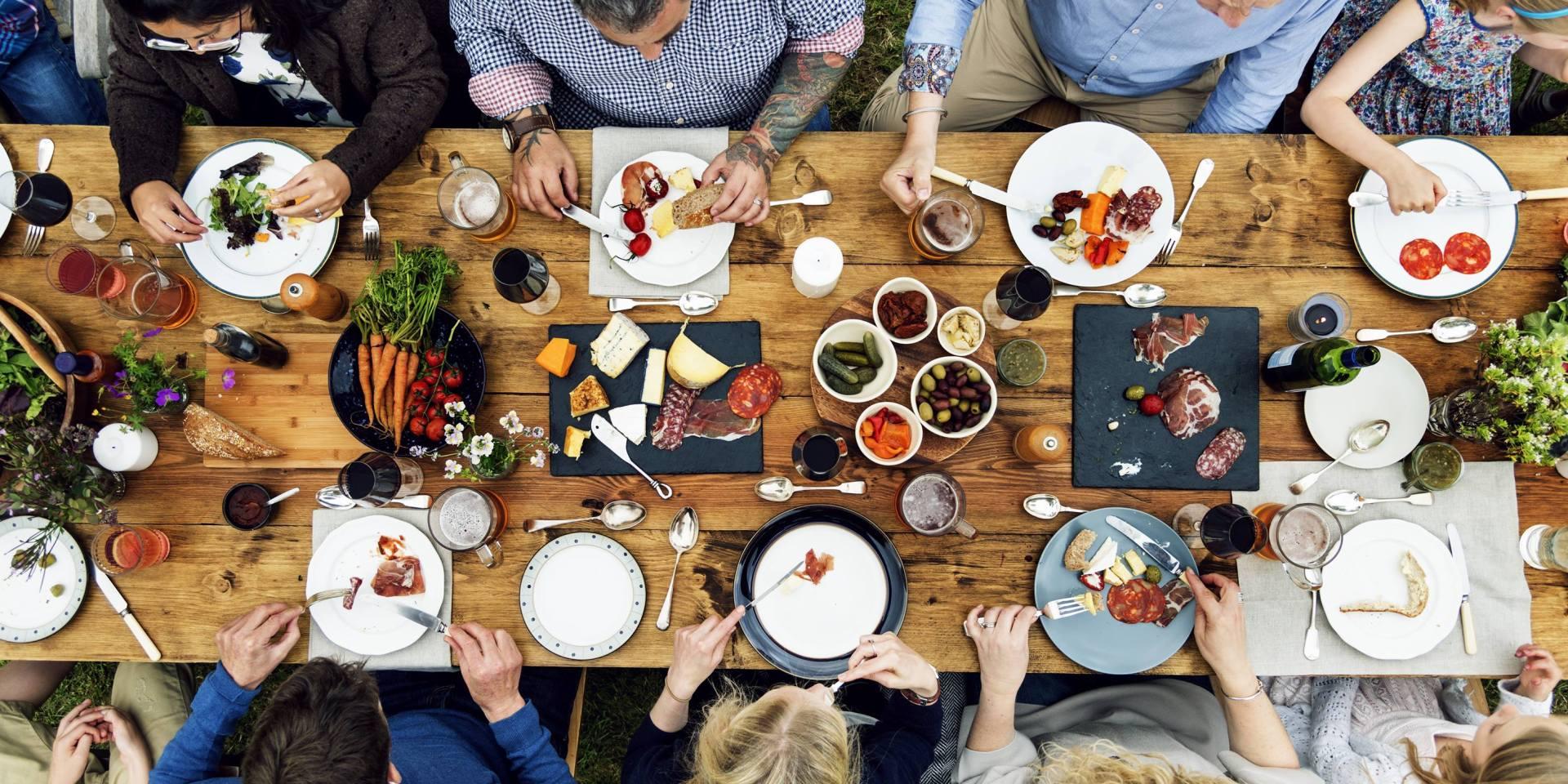 Overhead view of people sharing food at a long wooden table
