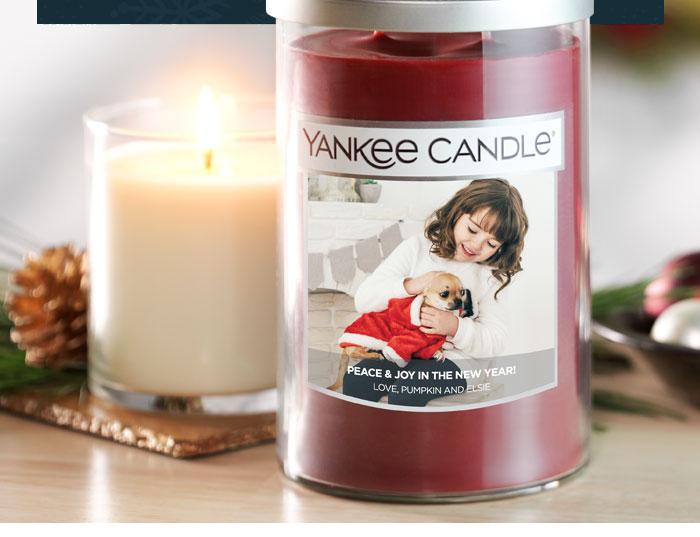 Yankee Candle jar with custom label beside a lit candle and holiday decor
