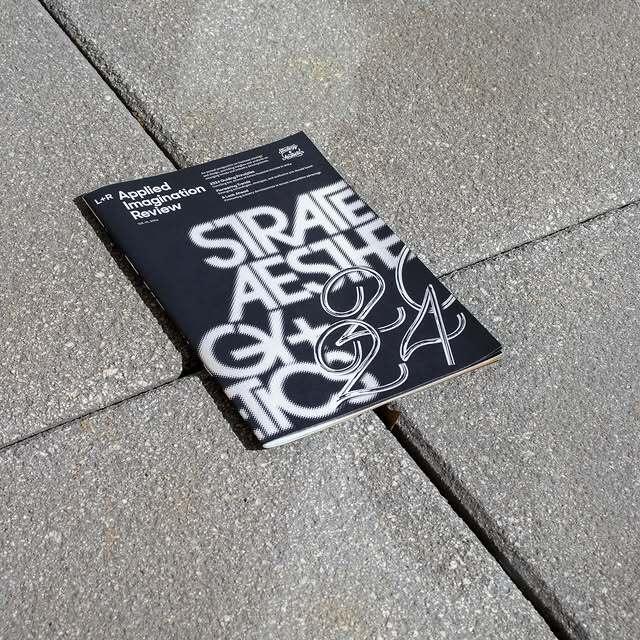 Black typographic booklet lying on a concrete floor