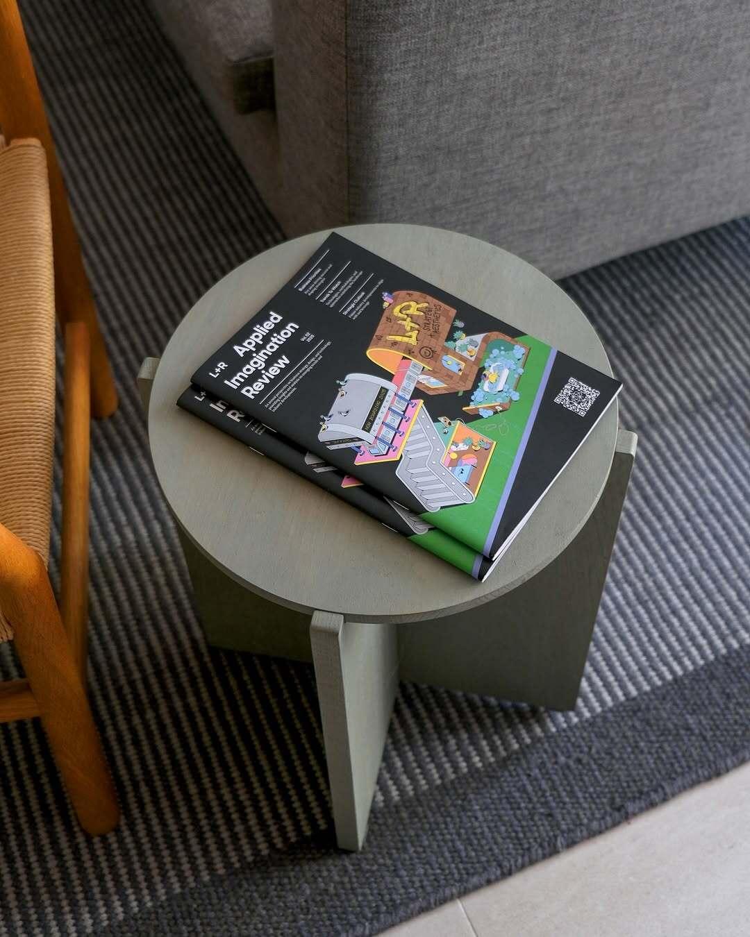 Magazine and cards on a small round table beside an upholstered chair