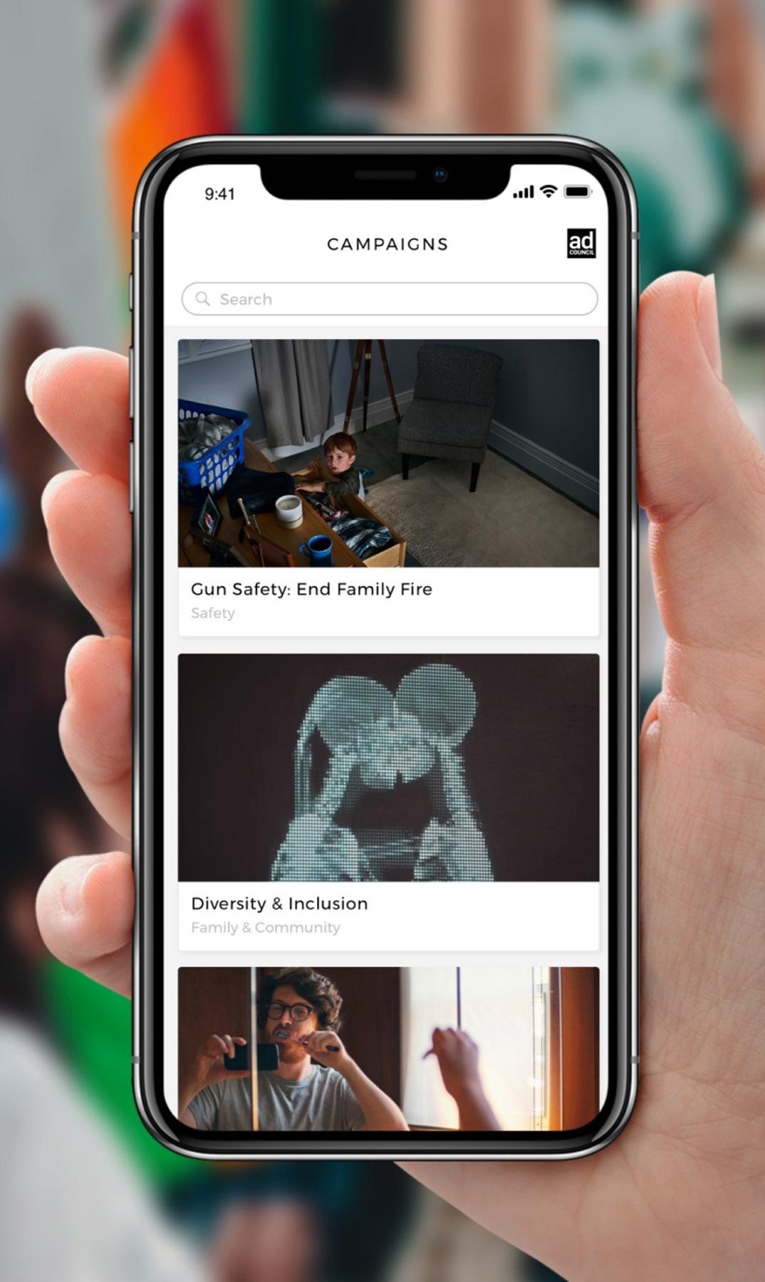 Hand holding a phone showing a campaigns list app
