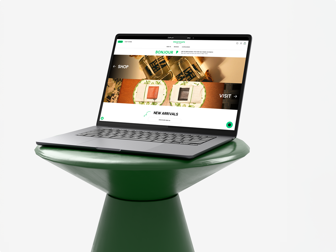 Open laptop on a green pedestal showing a retail website homepage
