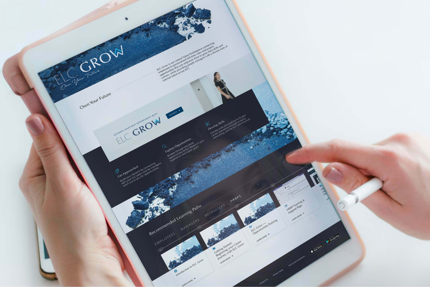 Hands using a stylus on a tablet showing the FLC Grow website.