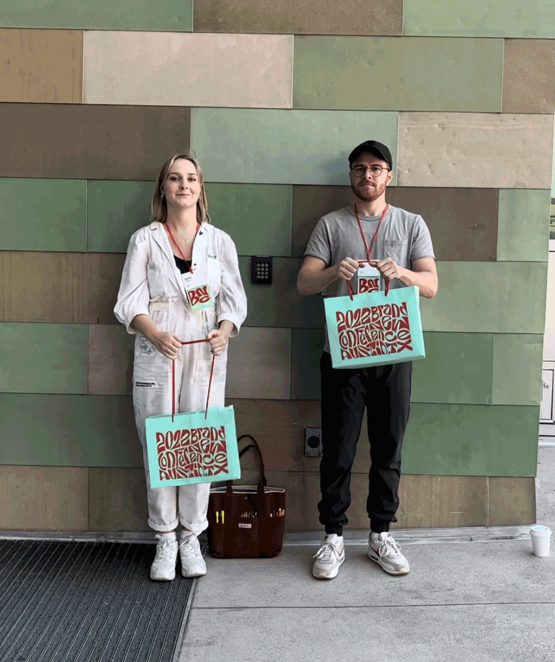 Two attendees holding 2022 Brand New Conference tote bags