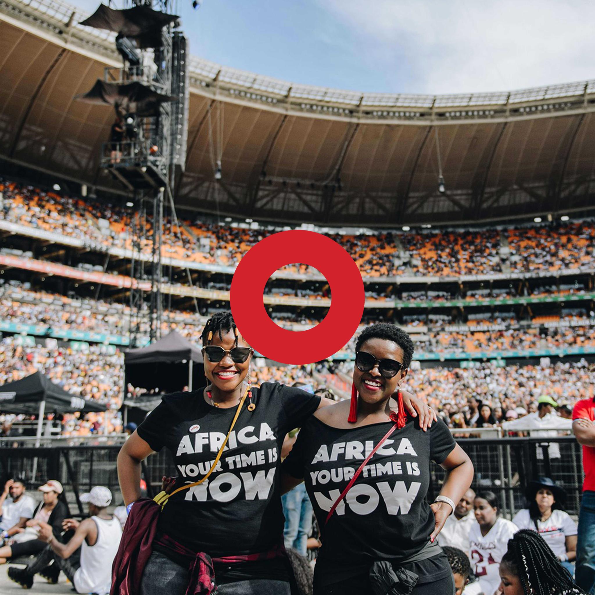 Two women in Africa Your Time Is Now shirts in a crowded stadium with a red ring overlay