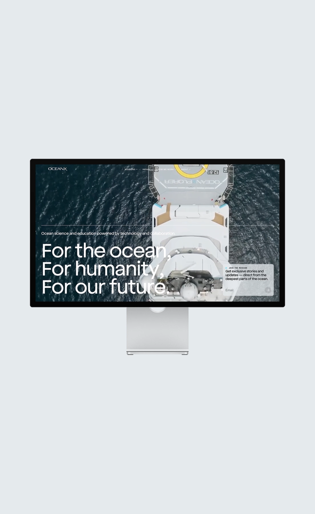 Desktop monitor displaying an OceanX homepage with aerial ship view and ocean slogan.