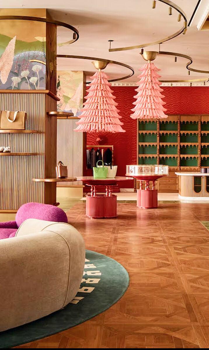Luxury retail interior with pink chandeliers, red displays, and wood flooring
