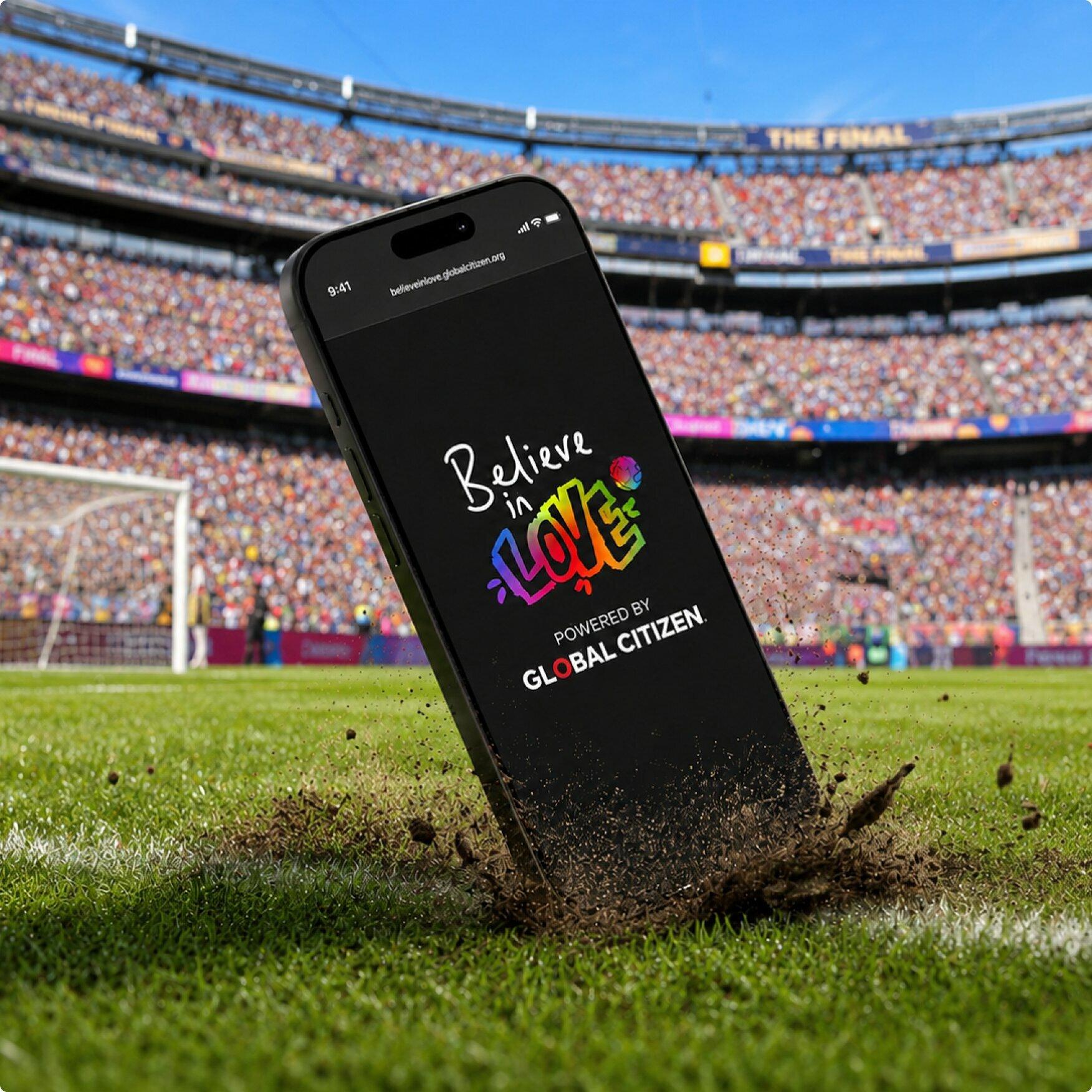 Phone standing on stadium turf with the Believe in Love app open.