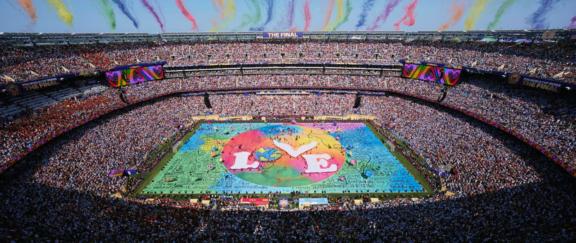 Packed stadium with a colorful Believe in Love display on the field.