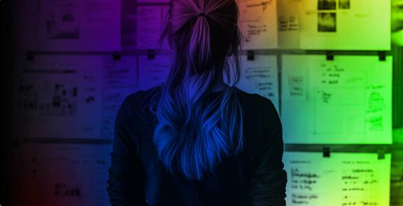 Person viewed from behind facing a wall of notes and sketches