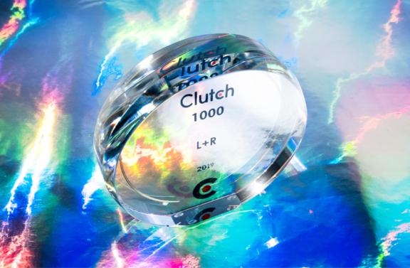 Close-up of a Clutch 1000 glass award on a colorful reflective surface