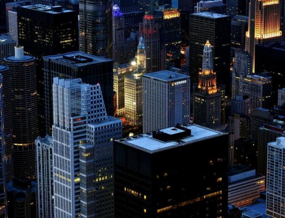Downtown skyscrapers at dusk with illuminated office towers and city lights