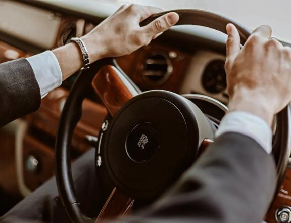 Hands on a Rolls-Royce steering wheel inside a luxury car