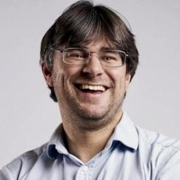 Smiling man with glasses in a light blue collared shirt.