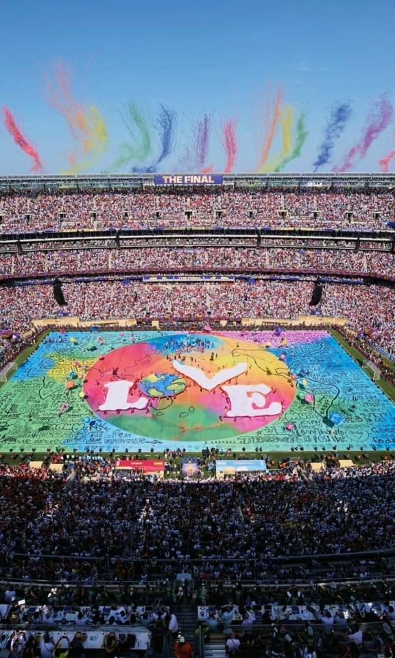 Packed stadium with a colorful Believe in Love display on the field.