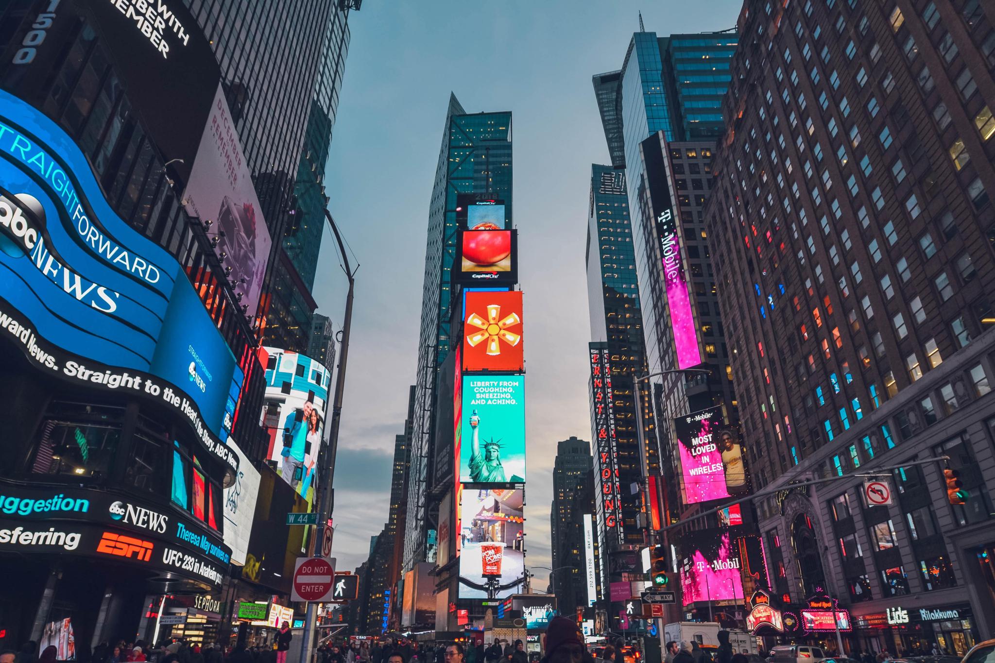 Times Square at dusk with illuminated billboards and tall buildings