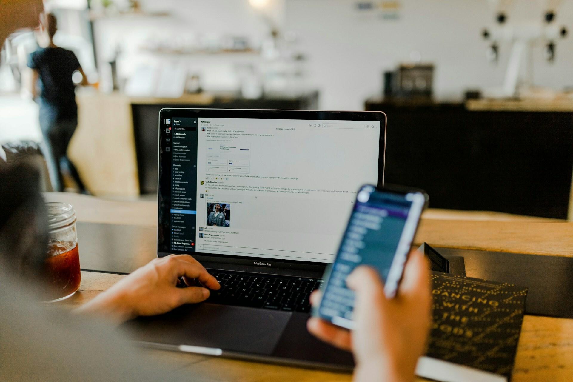 Person using a laptop and smartphone at a caf table