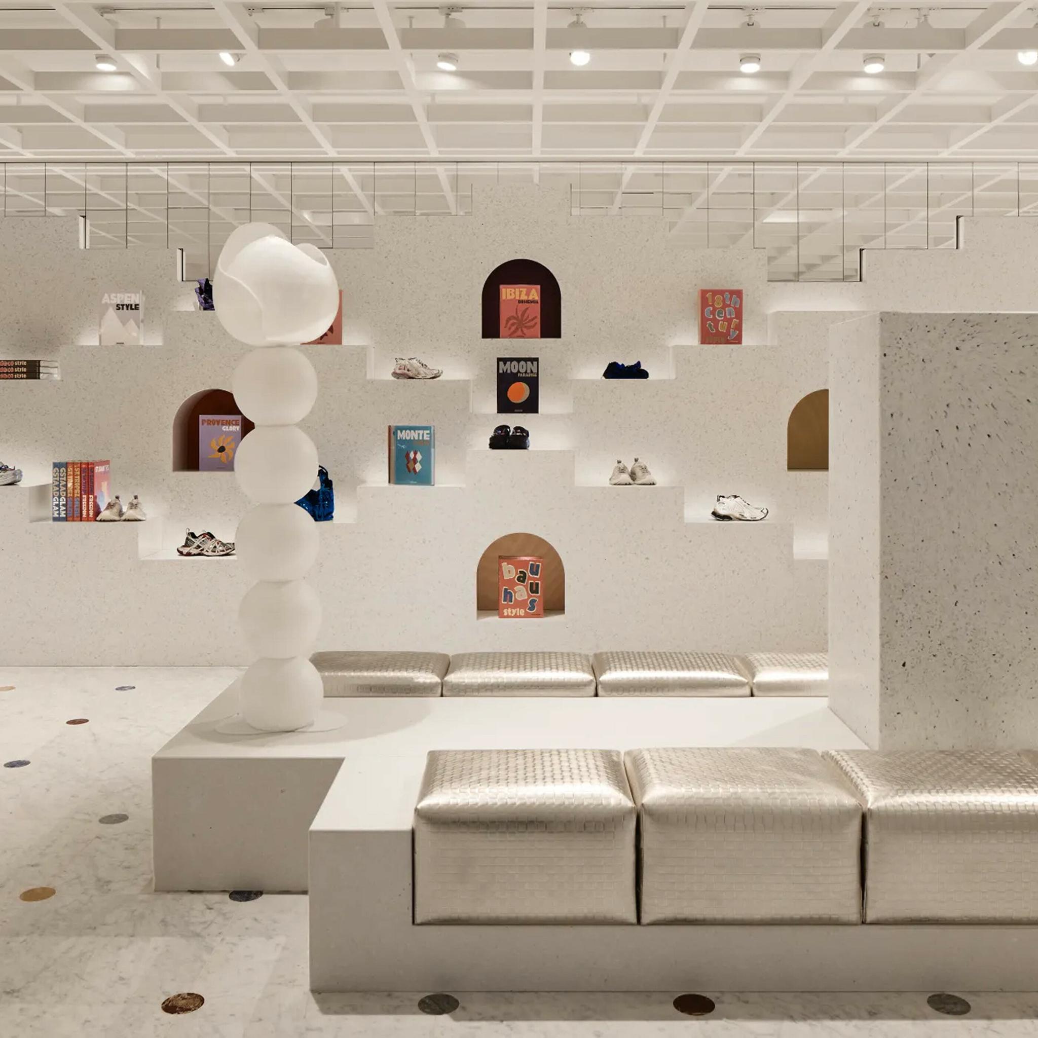 Bright white retail interior with shelves, sneakers, books, and cushioned benches