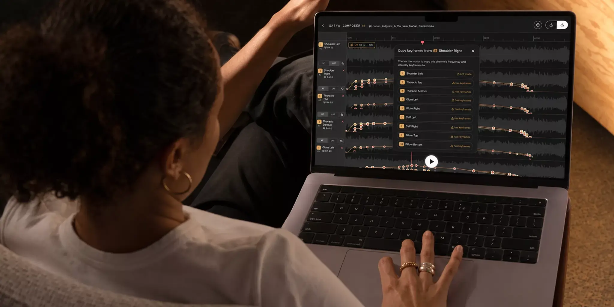 Laptop on a sofa displays Composer waveform tracks and playback controls.