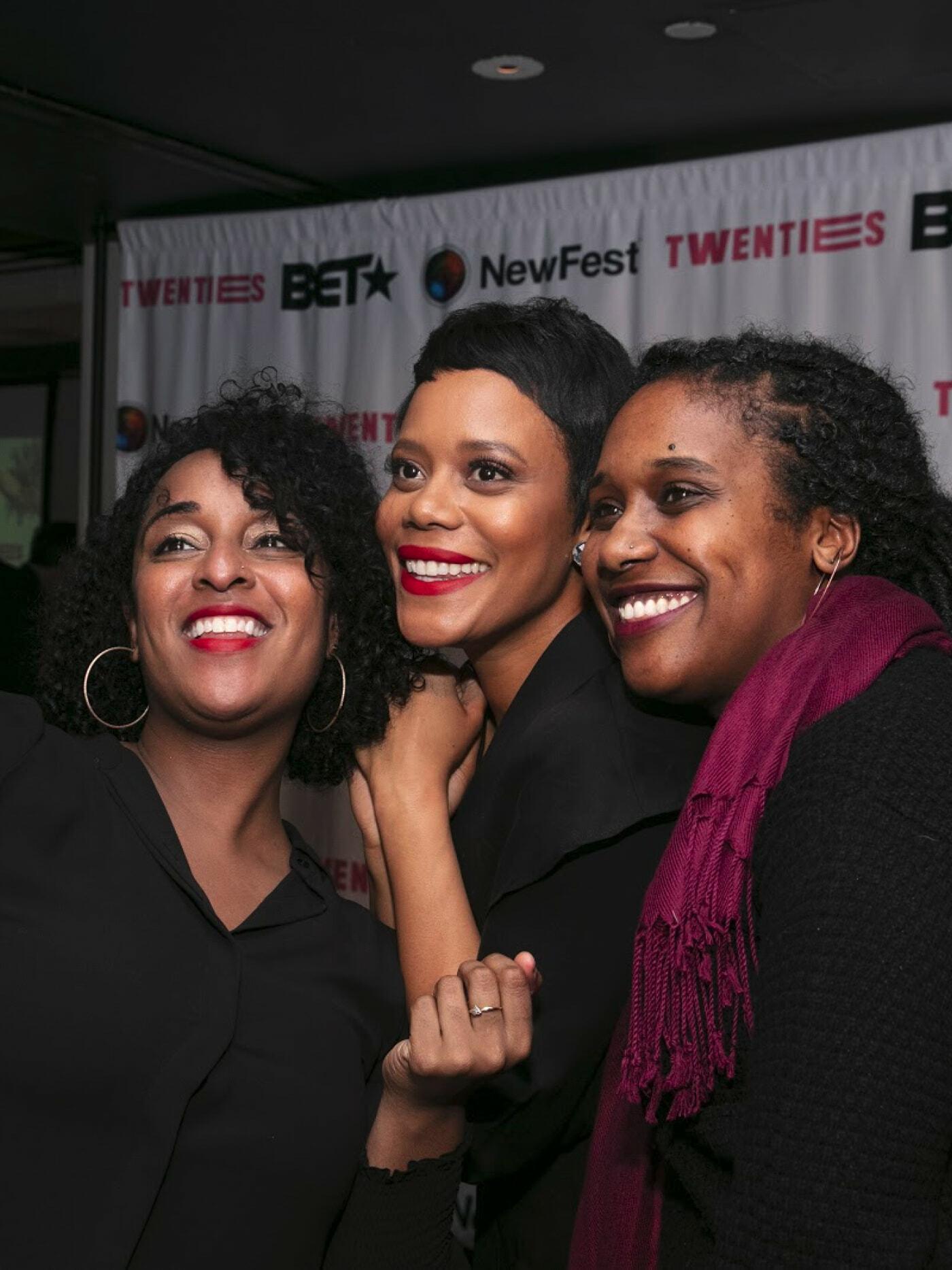 Three smiling attendees pose in front of a NewFest and BET step-and-repeat backdrop