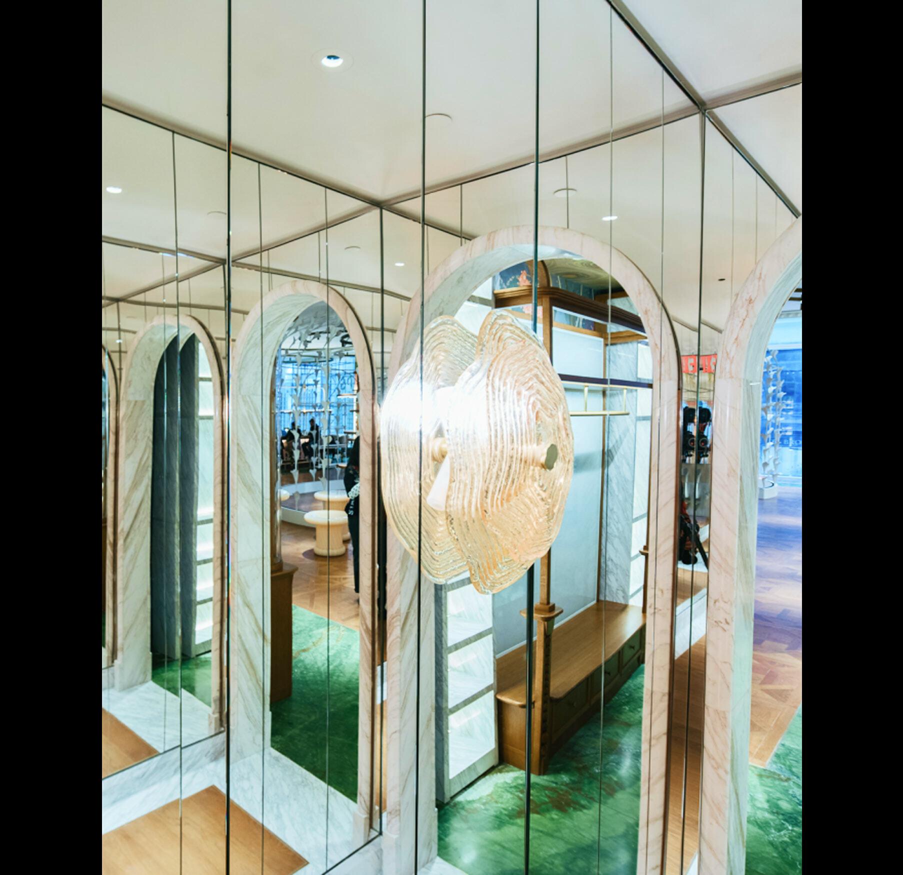 Mirrored corridor with arched openings and a glowing pendant light