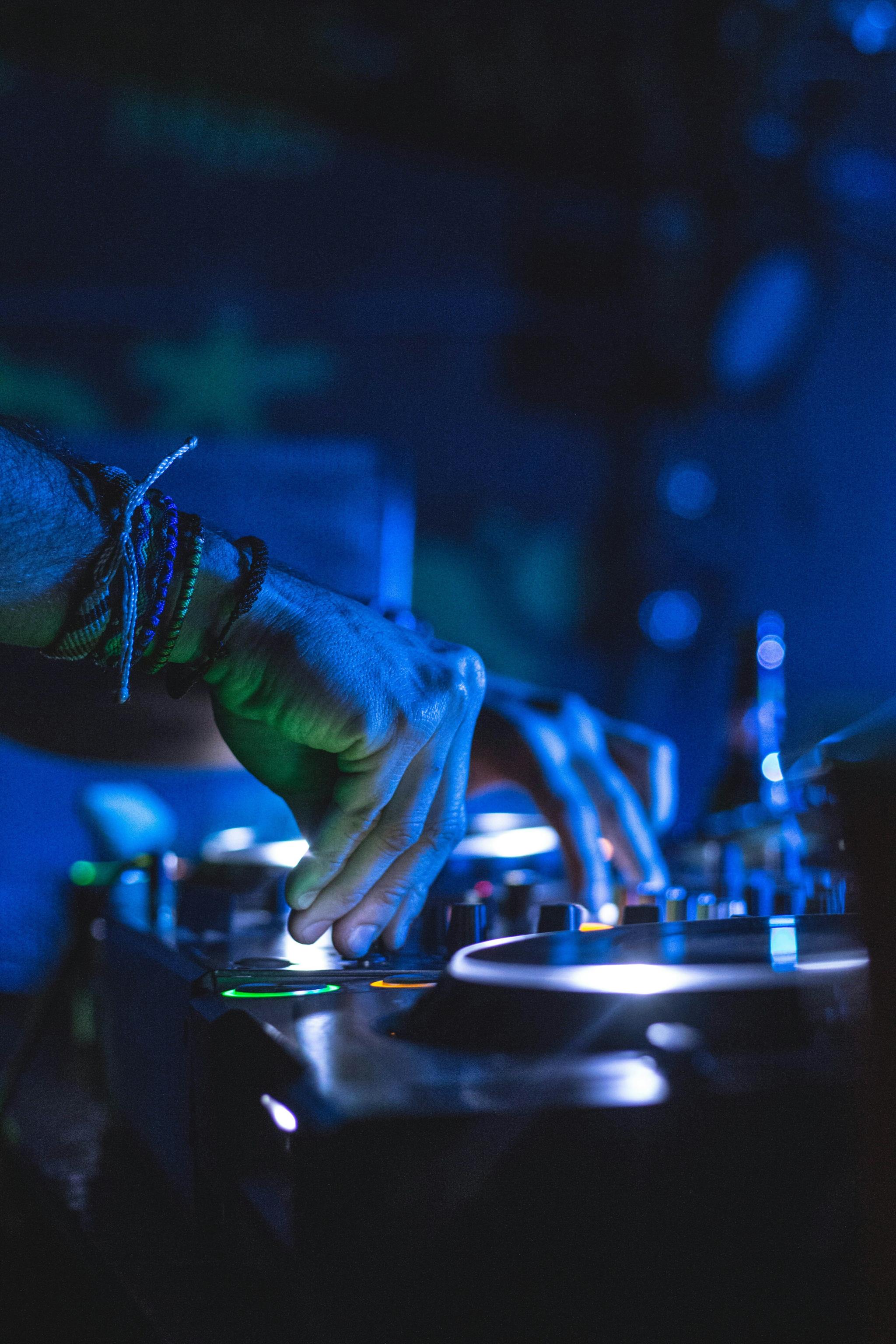 DJ's hand adjusting controls on a blue-lit turntable