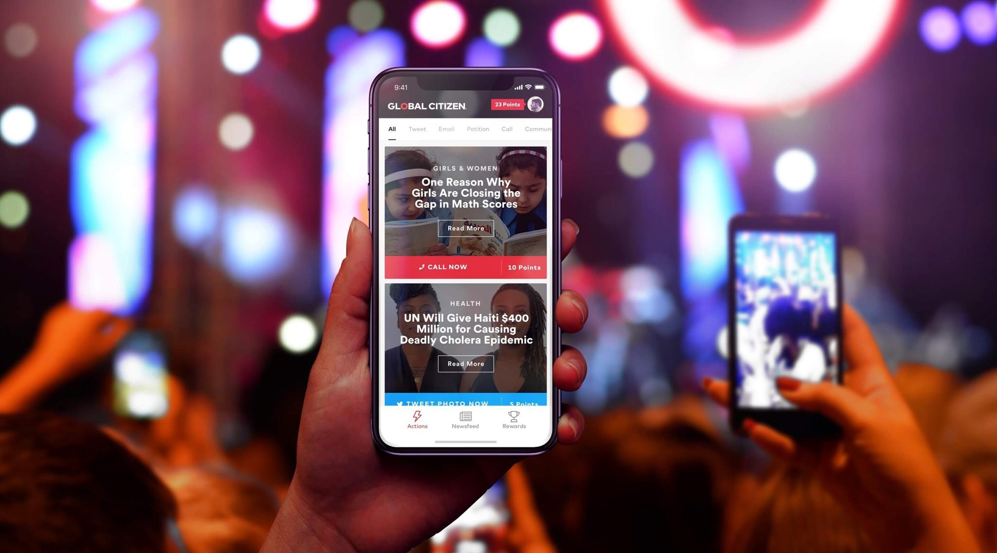 Hand holding a phone with Global Citizen app open in a concert crowd