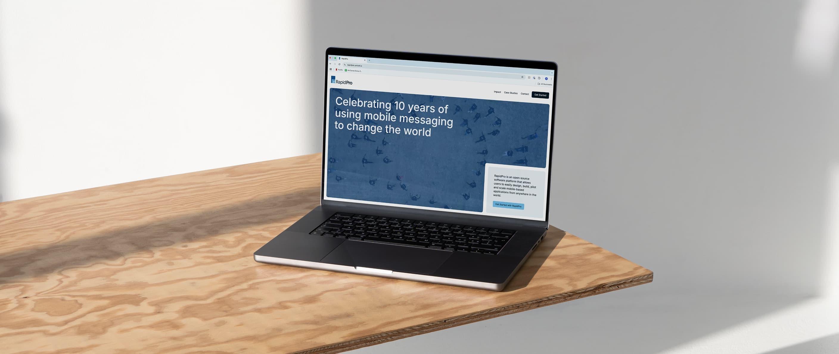 Laptop on a wooden table showing the RapidPro website