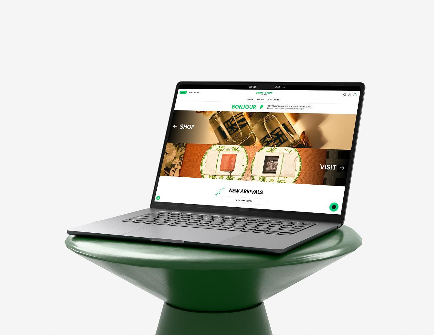 Laptop on a green pedestal showing a shopping homepage