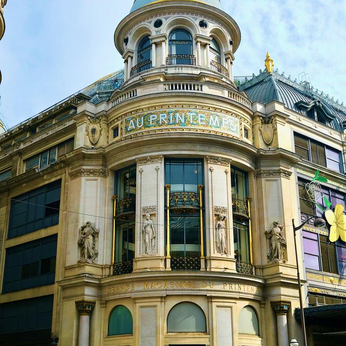 Ornate Au Printemps building facade with statues and arched windows