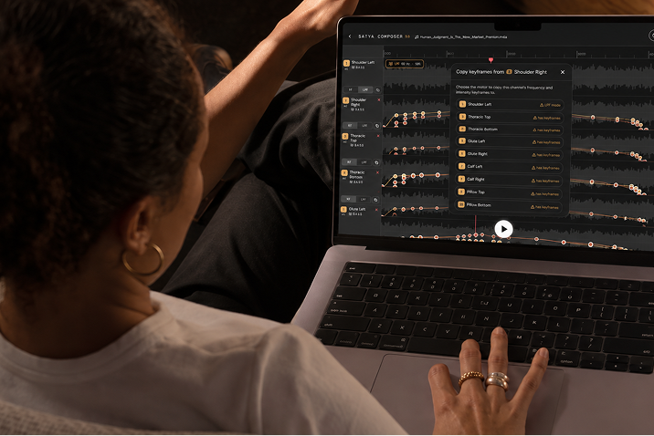Person uses a laptop with the Composer interface open on waveform tracks.