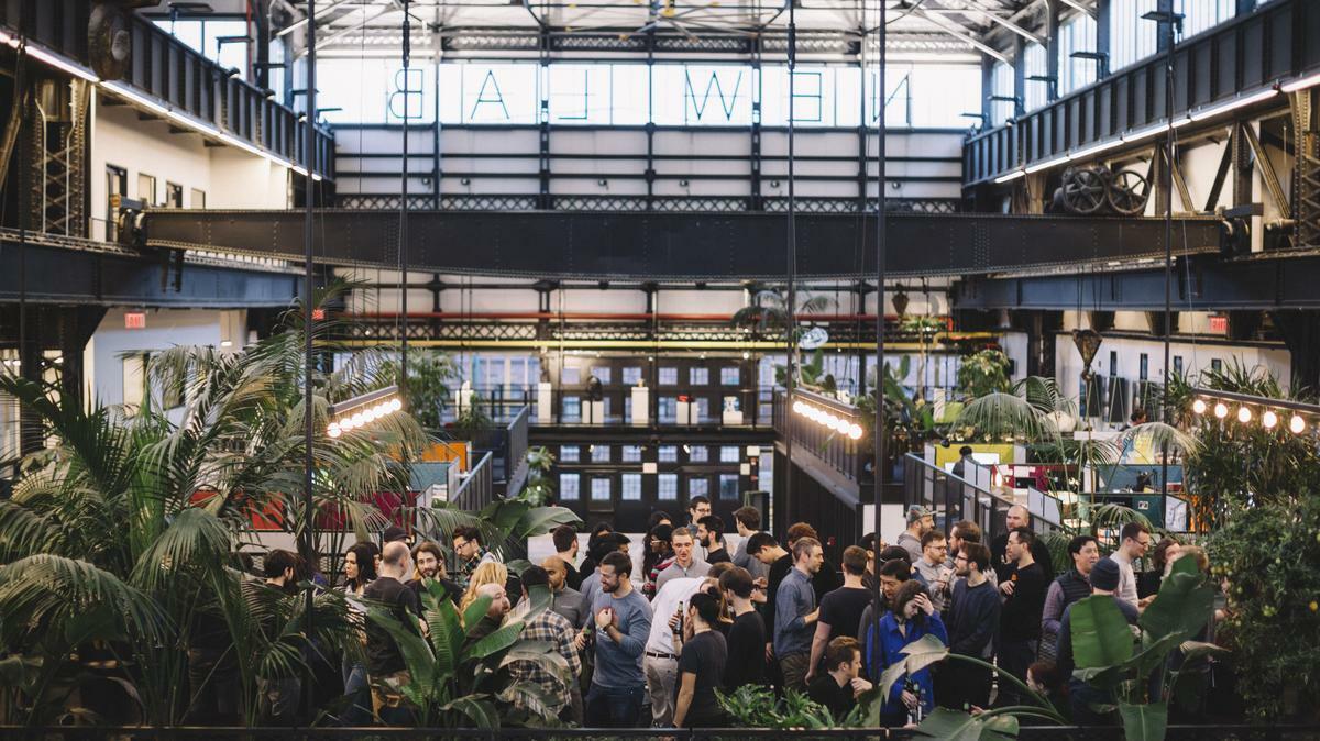 Crowd gathered inside an industrial hall with plants and glass ceiling