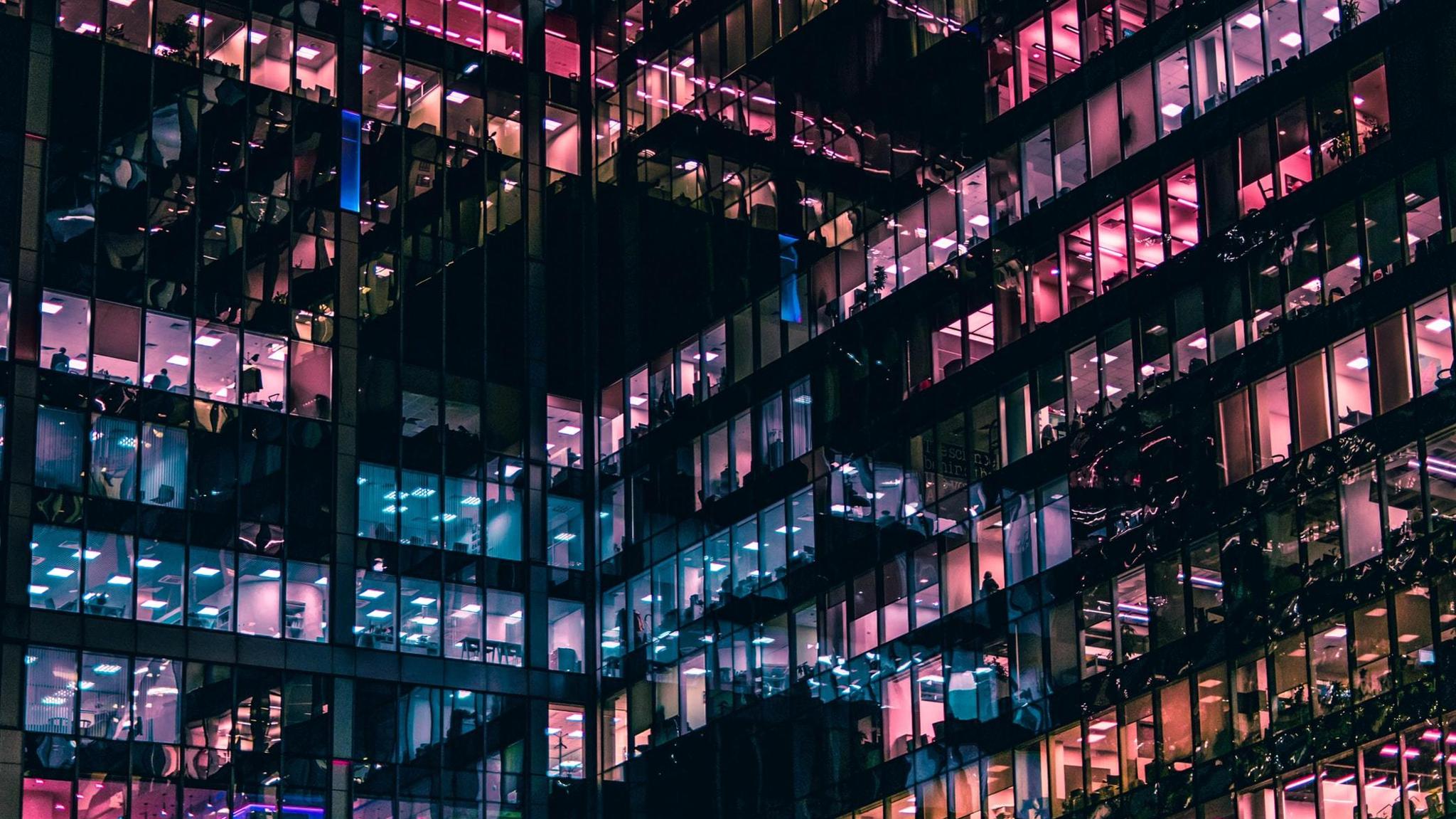 Office tower at night with pink and blue illuminated windows