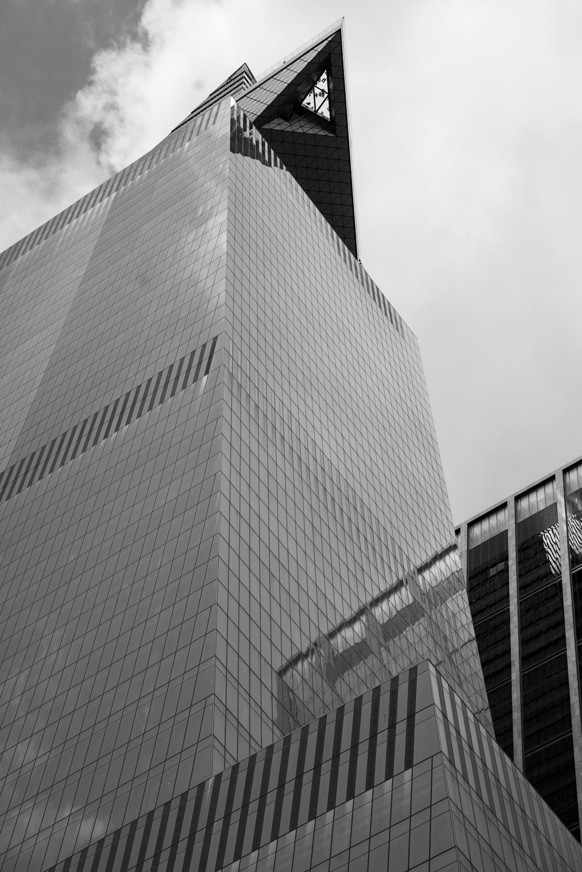 Black-and-white low-angle view of a glass skyscraper with a sharp triangular top