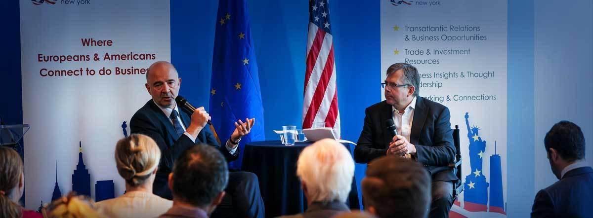 Business panel discussion with EU and US flags behind speakers
