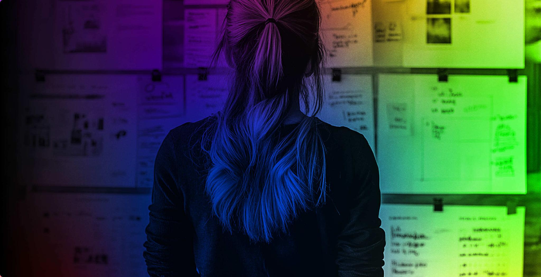 Person viewed from behind facing a wall of notes and sketches