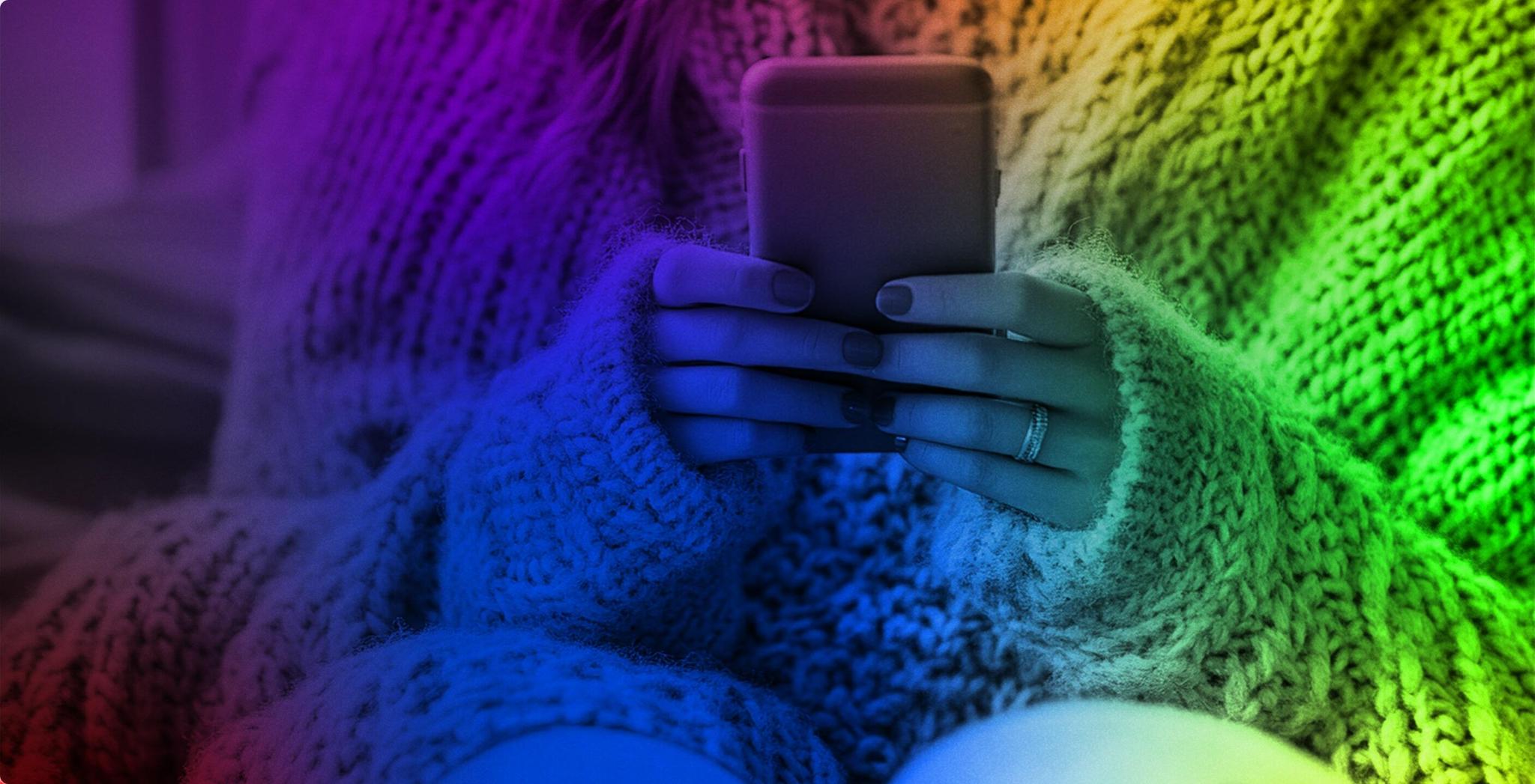 Hands holding a smartphone while wearing a chunky knit sweater