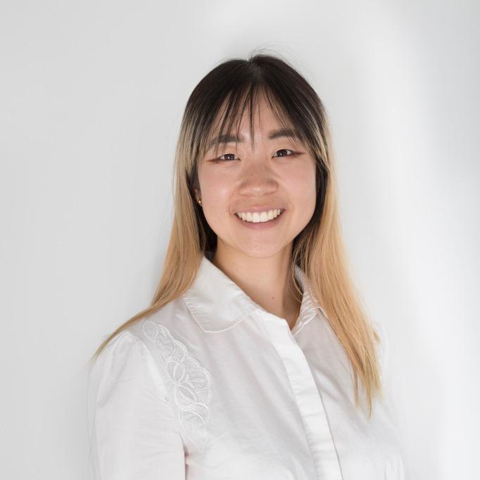 Smiling woman in a white shirt against a plain light background