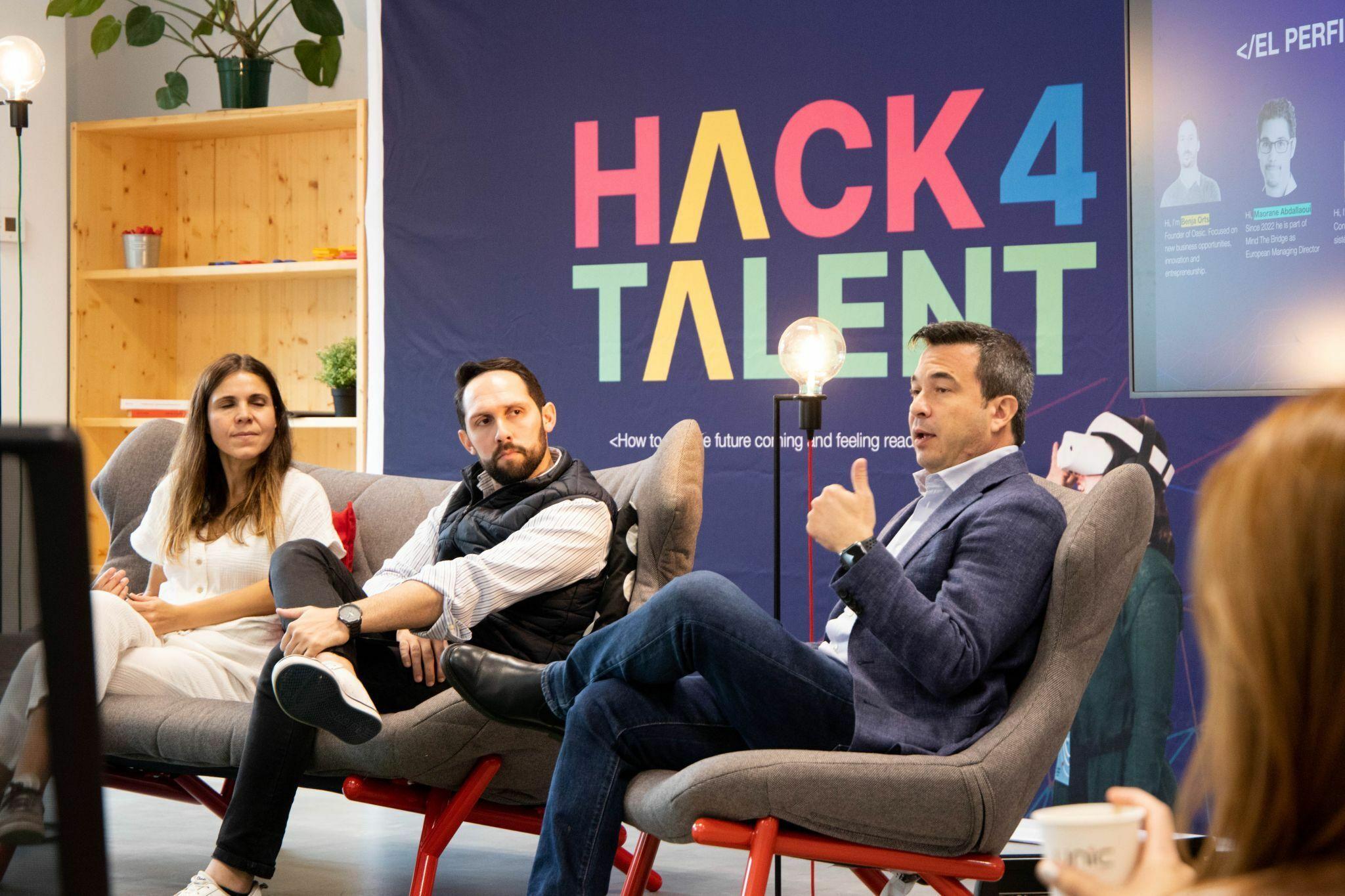 Panelists seated in armchairs in front of a Hack4Talent backdrop.
