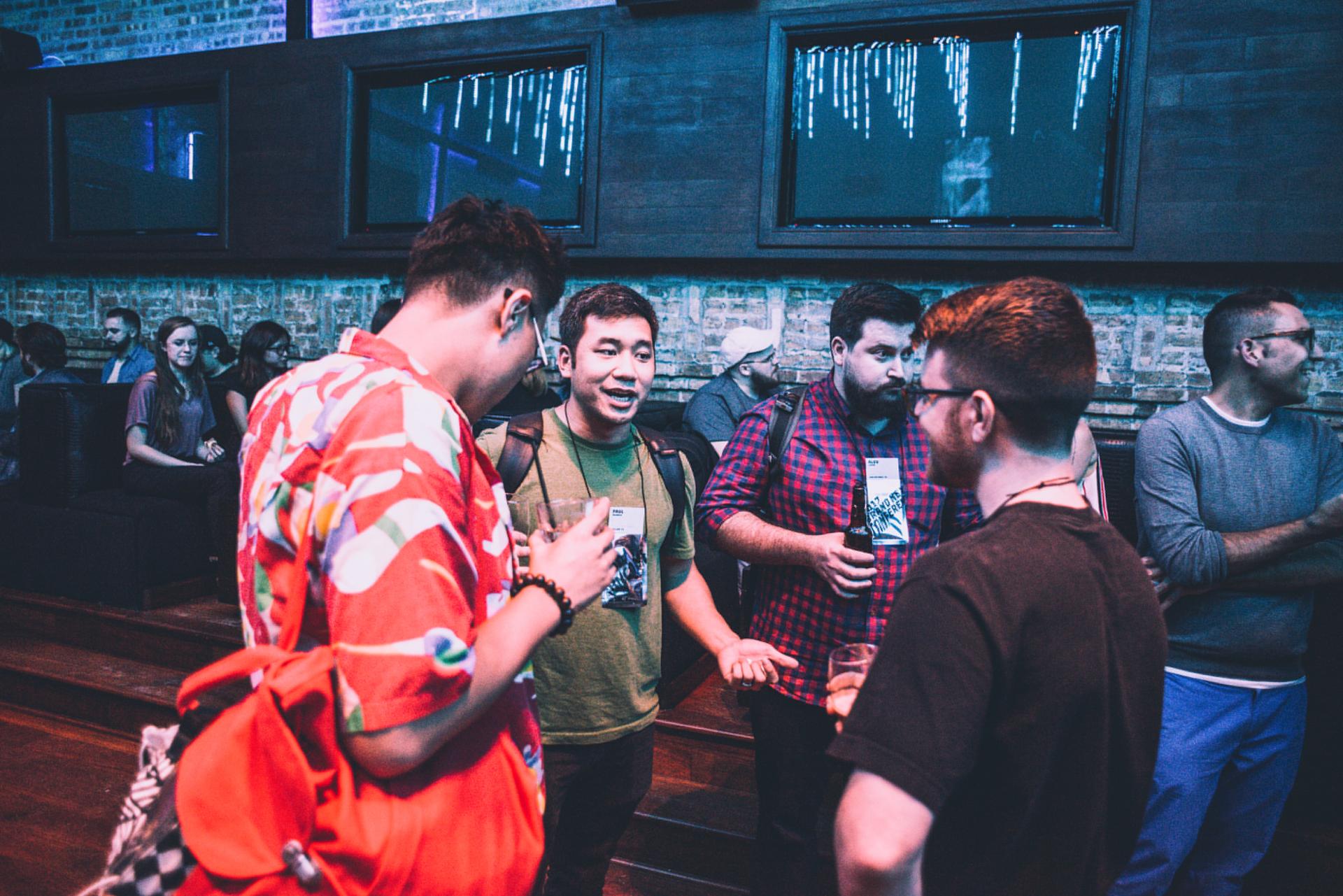 Group of people chatting with drinks at a dimly lit bar or event space