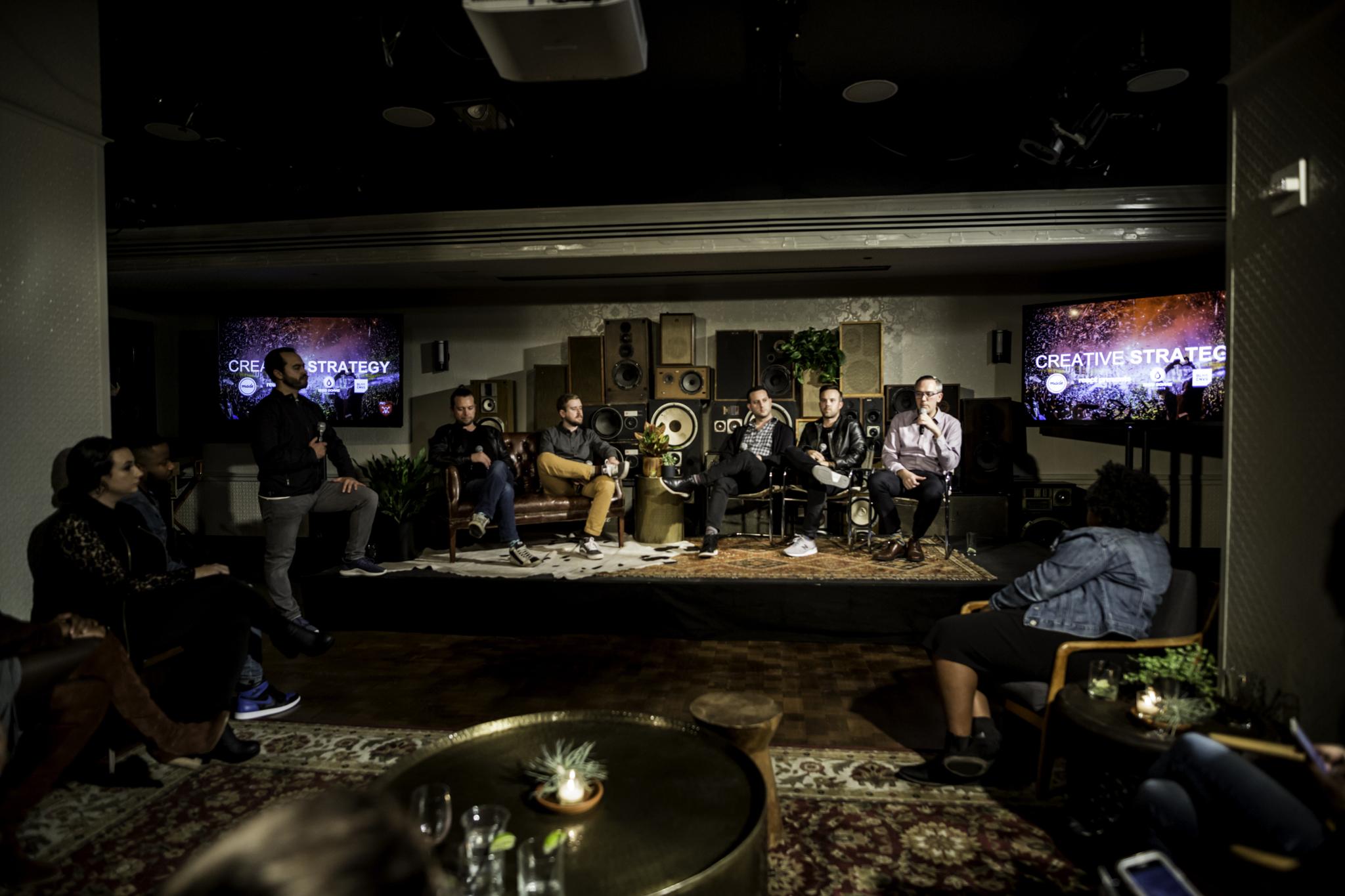 Panel discussion in a dim lounge with Creative Strategy screens