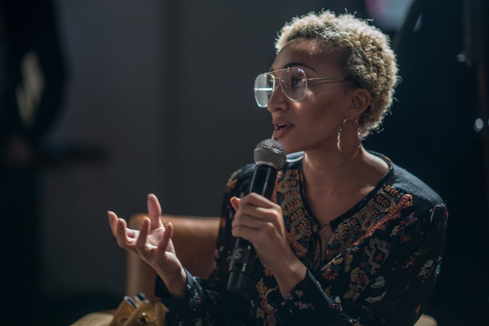 Woman holding a microphone while speaking at an event