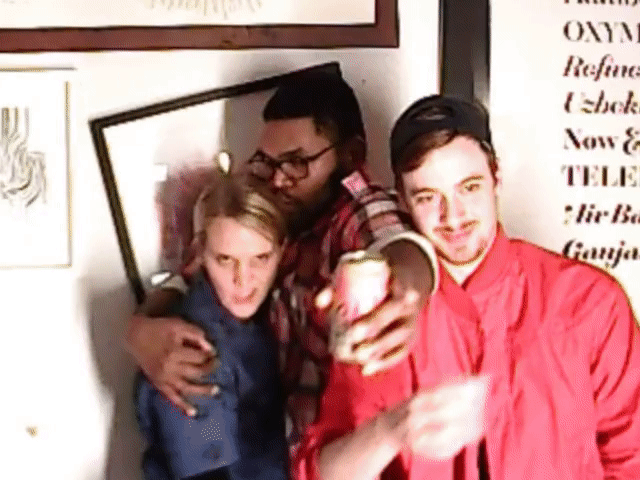 Three people posing for a selfie indoors with framed wall art behind them