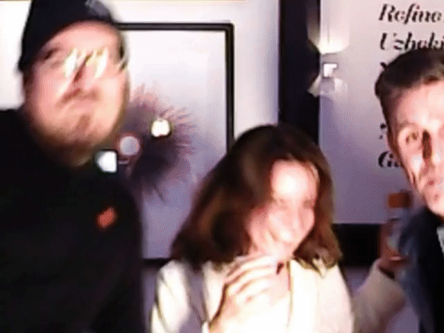 Three people posing close to the camera in a dimly lit room