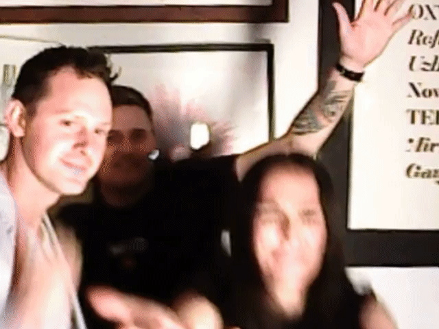 Blurry group of people indoors, one waving near framed wall art