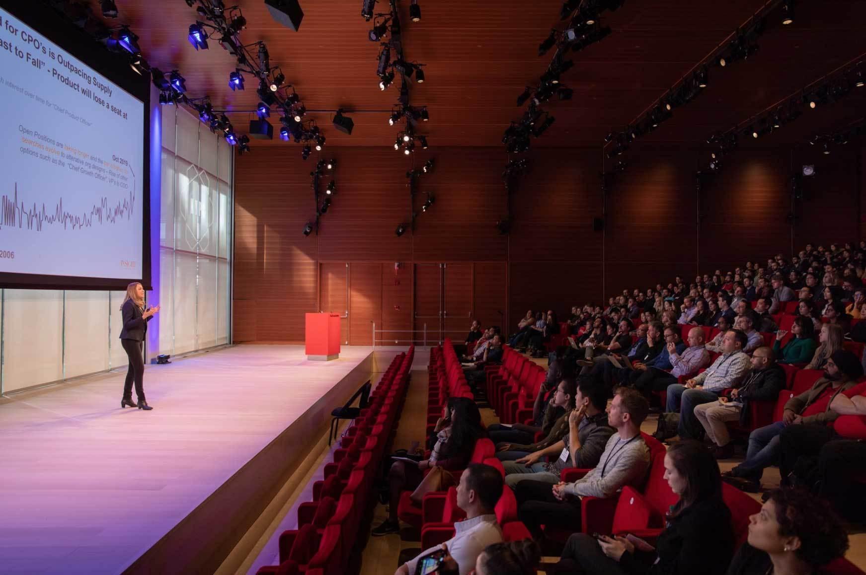 Speaker presenting to a large audience in an auditorium