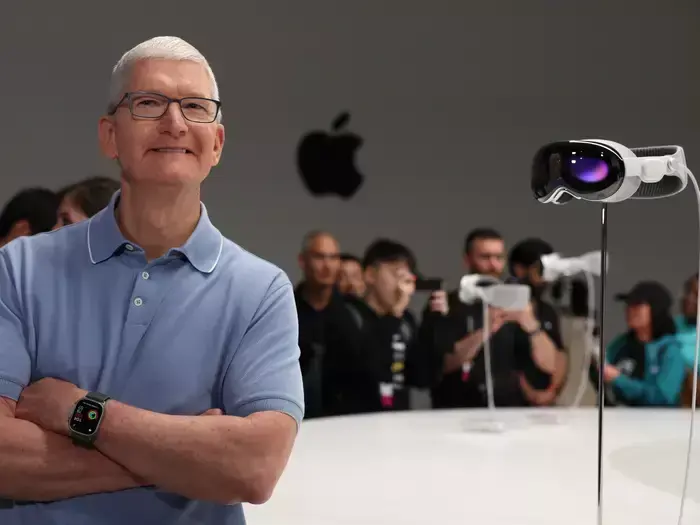 Man in blue polo beside an Apple Vision Pro headset display in an Apple event space