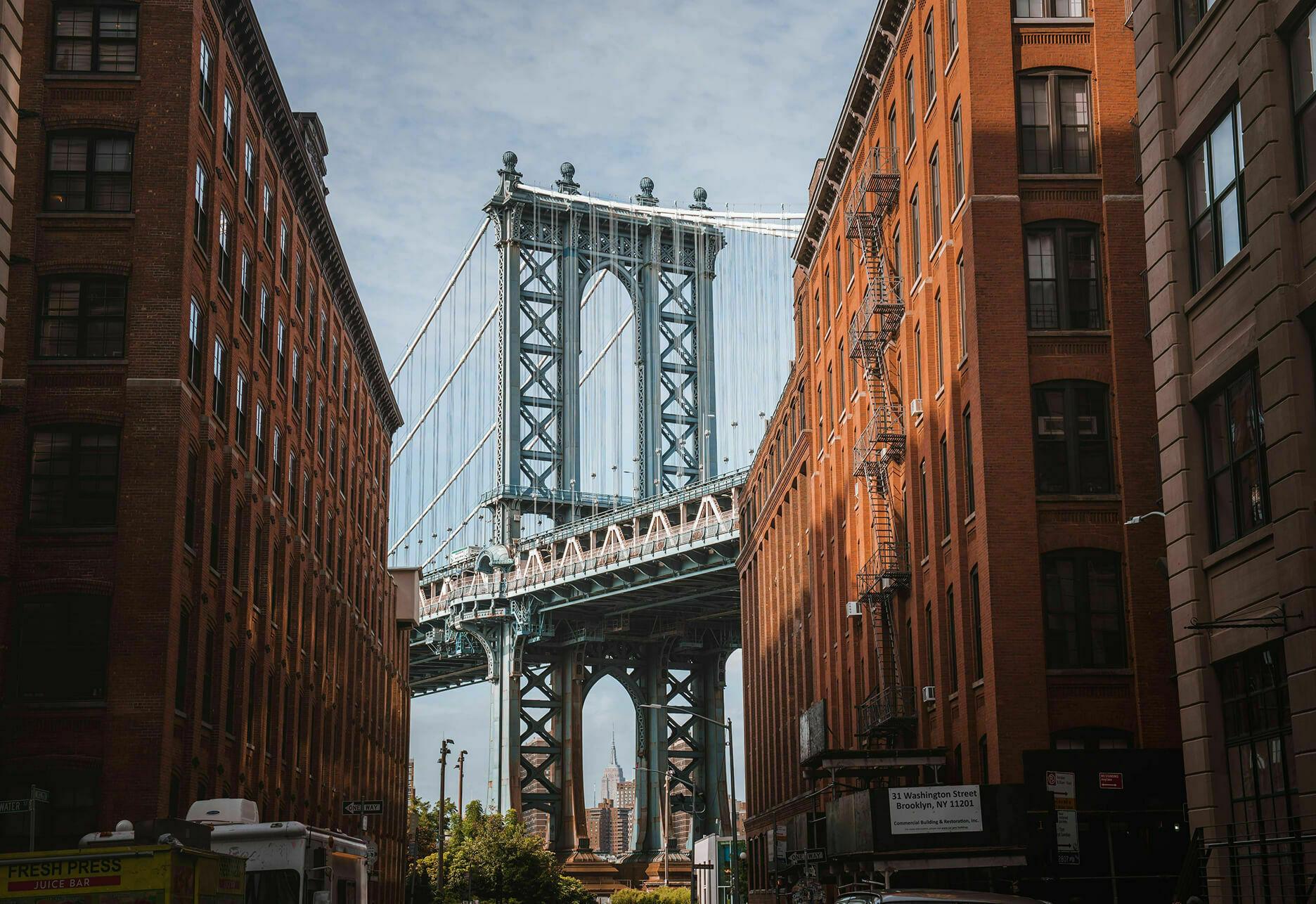 Manhattan Bridge framed by red brick buildings on a city street