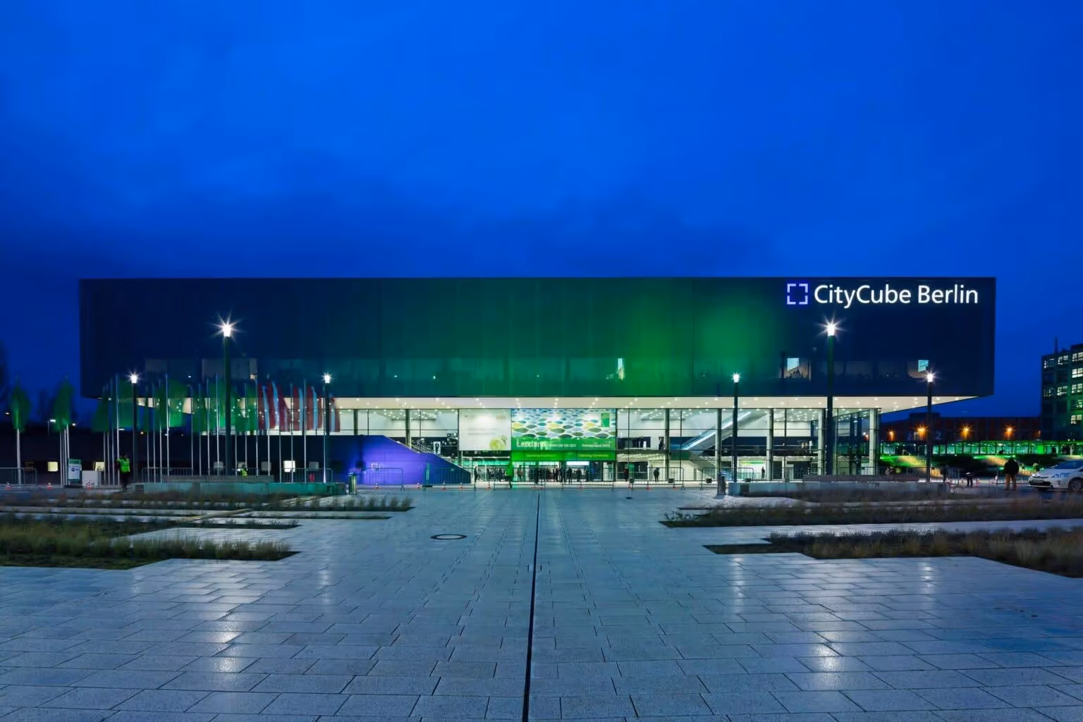 CityCube Berlin exterior lit at night beside a wet plaza.